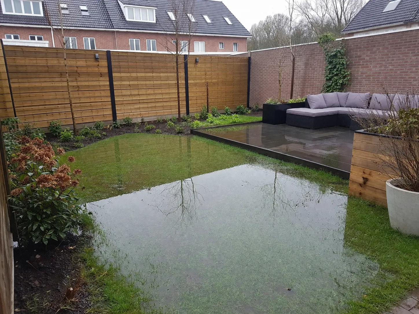 Realistische foto van een achtertuin met plasvorming op het gazon na hevige regen.