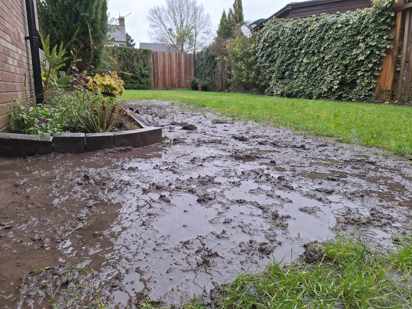 Een realistische tuin met natte kleigrond, plassen en modder na regen.